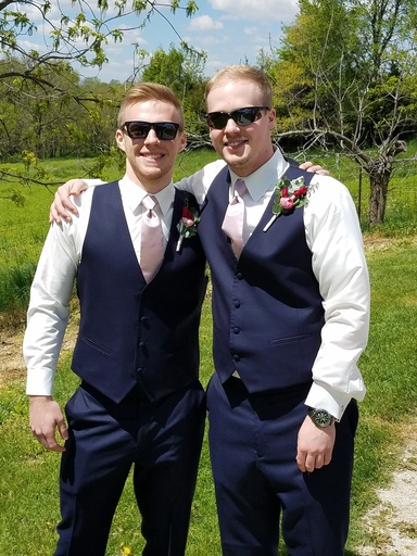 Marshall and Garrett Rupe. They are dressed up for a wedding and have their arms around each other.
